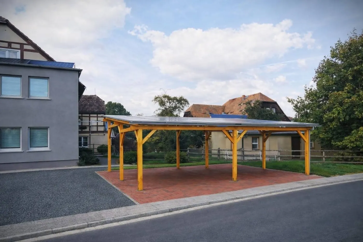 Drewniany carport fotowoltaiczny przy budynku mieszkalnym